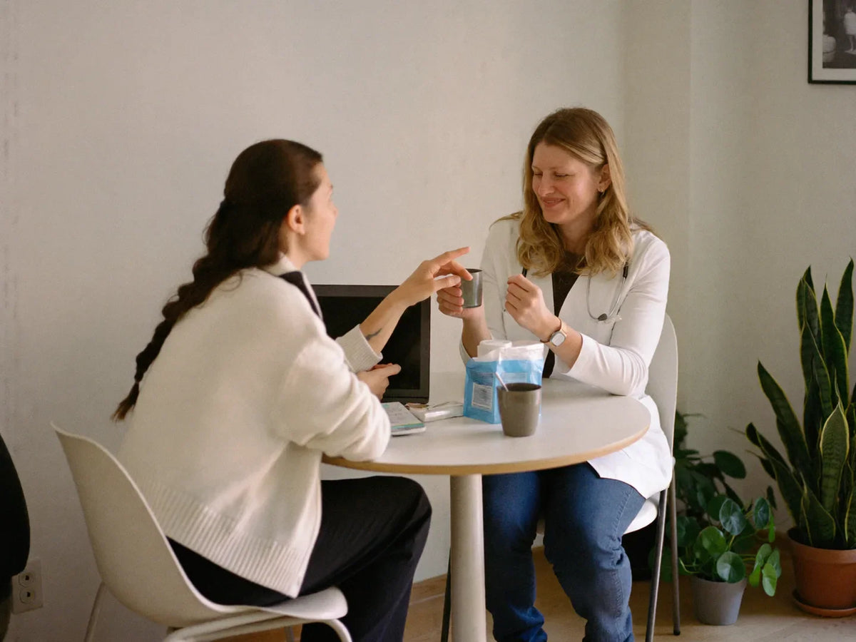 Woman talking with a doctor at a small table in a bright consultation room