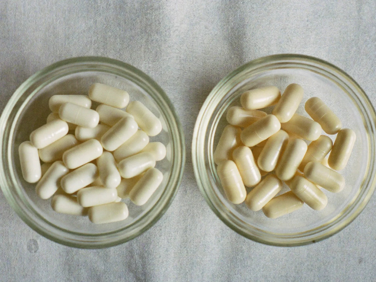 Two glass bowls of white capsules side by side on linen